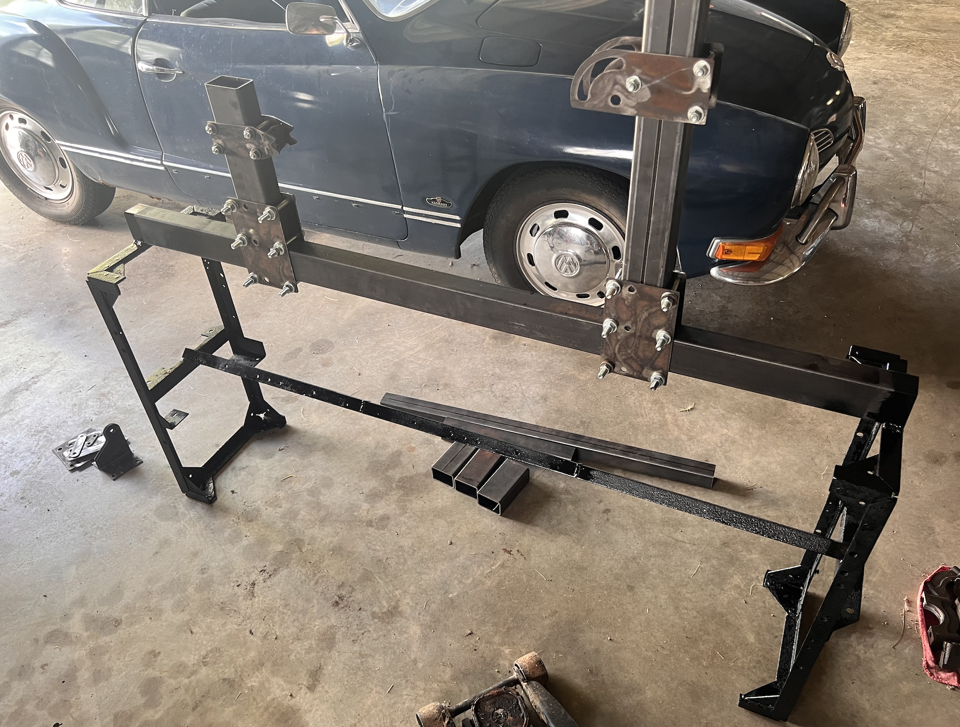 Welded steel bike frame jig with bolted fixture plates in a garage.