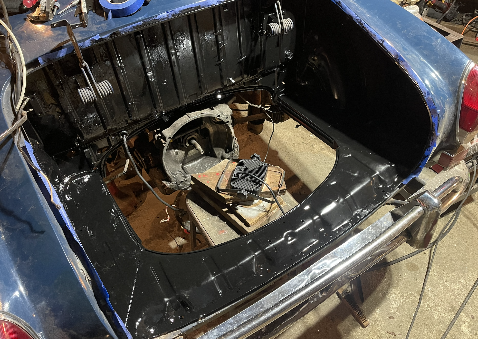 Freshly painted black Karmann Ghia engine bay during restoration.